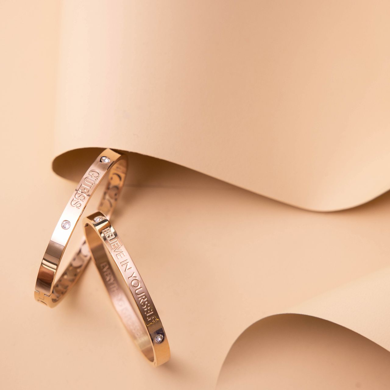 Rotvergoldeter Bangle-Armreif aus Edelstahl von Guess mit Text: Believe.