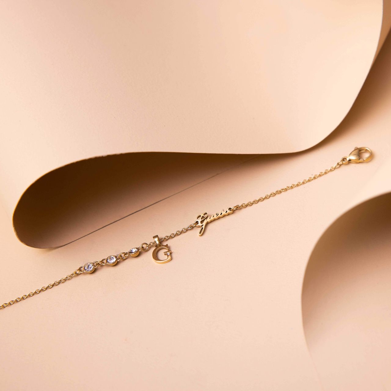 Guess stalen goldplated fantasiearmband met letterhanger met kristal voor dames